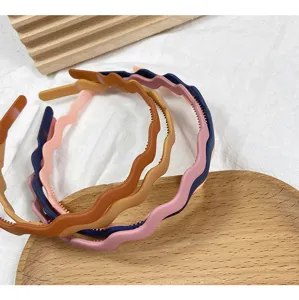 Close-up detail of stylish matte wavy plastic hairbands in assorted candy colors for women.