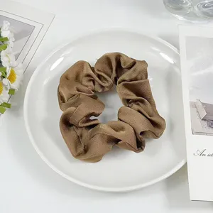 Brown satin hair scrunchie detail view, elegant hair tie accessory showcasing soft fabric.