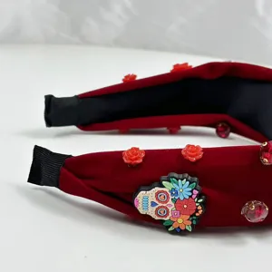 Red velvet Halloween headband with skull and roses, wide knotted festive hair accessory.