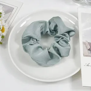 Detailed view of elegant light green satin scrunchie, smooth texture for hair styling and wear.