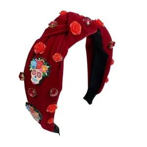 Close-up of red velvet headband featuring sparkling rhinestones, floral details, and skull charms.