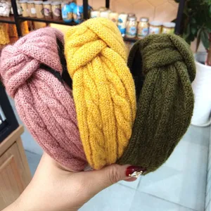 Detailed view of knitted braided headbands in pink yellow and dark green. Soft fabric hair accessories.