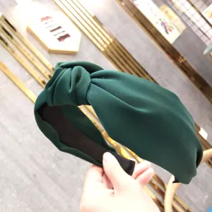 Detailed shot of dark green fabric knotted headband, highlighting wide soft texture design.