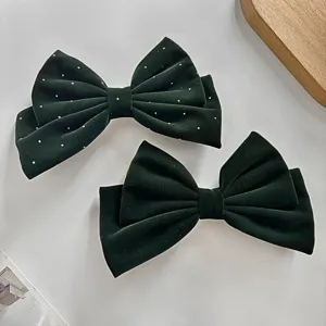 Pince à cheveux nœud en velours vert foncé avec strass et style minimaliste élégant.