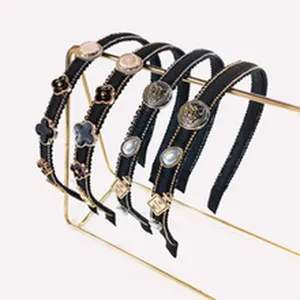 Stylish black headband set featuring elegant clover and metal charms on gold tone stands.