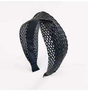 Vue détaillée d'un serre-tête croisé en paille noire, accessoire chic pour femmes.