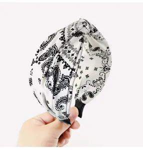 Primo piano dettagliato della fascia per capelli in tessuto paisley bianco e nero.