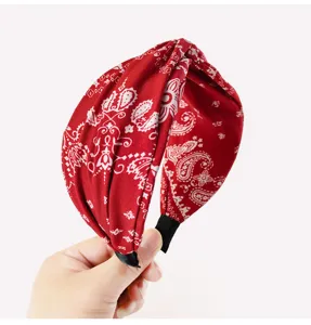 Cerchietto in tessuto rosso con stampa cachemire, dettaglio fascia intrecciata per donne.