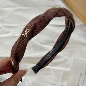 Detail shot of brown knitted headband with cute gold bows, showing fuzzy plush texture.