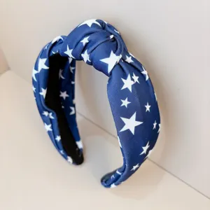 Primo piano dettaglio del cerchietto annodato con motivo a stelle blu e bianco, tessuto.