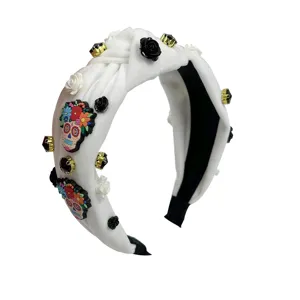 White velvet knot headband featuring colorful sugar skull patches and sparkling crystals detail.