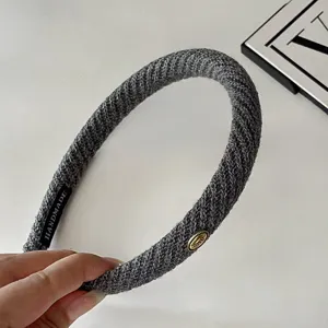 Detailed close up view of dark grey knitted twill thin hair hoop featuring metal charm.