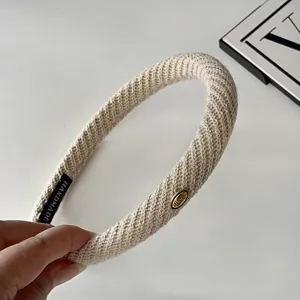 Detail shot of autumn winter wool twill thin headband with gold metal label, cozy hair hoop.