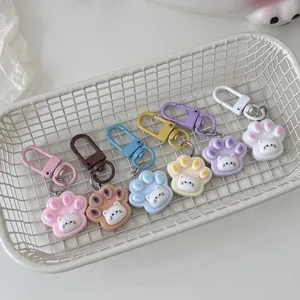 Primo piano dettagliato di simpatici portachiavi con zampe di gatto colorati in un cestino.