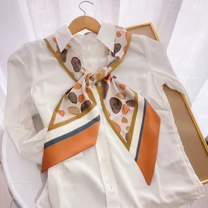 Detailed view of the elegant narrow silk scarf with abstract stone print and chic orange border.