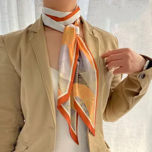 Close-up detail of stylish orange and white printed long silk scarf tied neatly on neck.