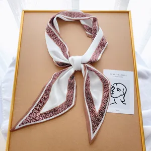 Detailed view of elegant white narrow silk ribbon scarf with chic brown geometric diamond border.