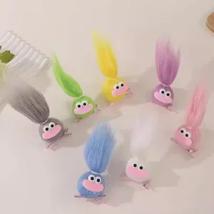 Primo piano dettaglio di graziose mollette per capelli bambola pelose divertenti con lunghi capelli.