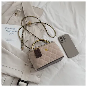 Detalle del bolso neceser acolchado con asa dorada y correa de cadena elegante.