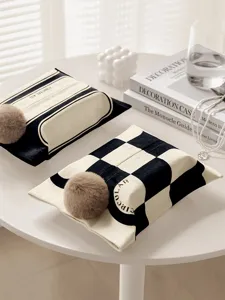 Close-up detail of black and white fabric tissue box with plush ball decor for home decor.