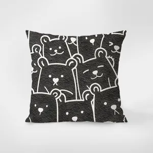 Gros plan sur les details du coussin de canape noir et blanc avec motif d'ours cartoon.
