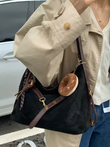 Minimalist black suede shoulder bag with brown straps and cute donut charm for women.