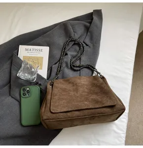 Detailaufnahme der minimalistischen Wildleder-Umhängetasche mit eleganter Kette und Braun.