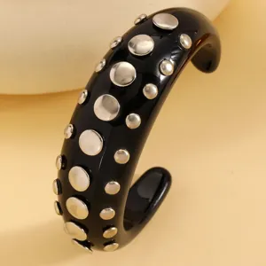 Black resin cuff bracelet with silver tone metal studs, punk style detailed jewelry piece.