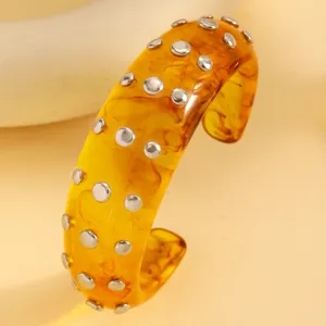 Amber marbled resin cuff bracelet with metal rivets, punk style fashion open bangle detail.