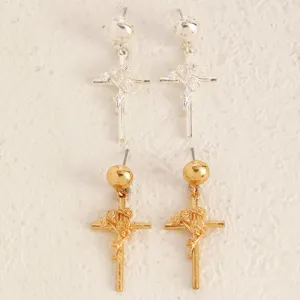 Gros plan de boucles d'oreilles croix en métal style gothique punk avec pendentifs roses.