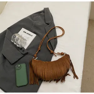 Brown suede fringe crescent shoulder bag detail view showing texture, strap and tassels.