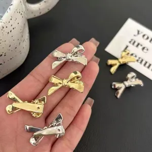 Gros plan detail de petites pinces a cheveux noeud metal dore et argente pour frange.