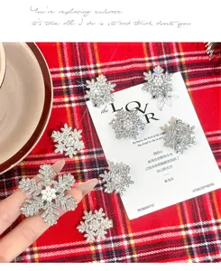 Close-up of sparkling rhinestone snowflake hair clips on red plaid backing card for details.