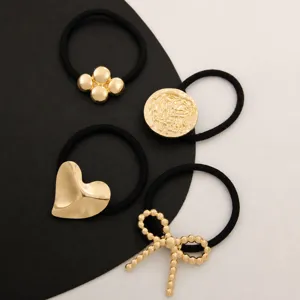 Set of 4 black hair ties with elegant gold metal charms including heart, bow, and disc designs.