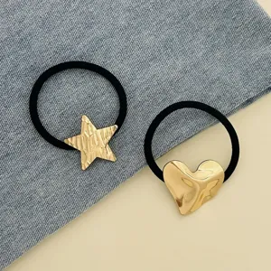 Detail shot of two black elastic hair ties featuring metallic gold star and heart charms.