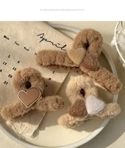 Detail view of cute autumn and winter plush hair claws with soft brown fabric and heart design.