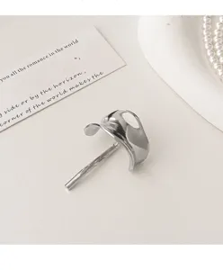 Detailed view of simple silver metal hair clip, elegant abstract ponytail holder accessory.
