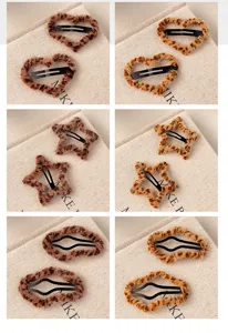 Gros plan détaillé de pinces à cheveux en peluche avec motif léopard cœur et étoile.