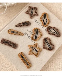 Détail de pinces à cheveux en peluche imprimé léopard, tissu doux avec attache métallique.