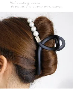 Large matte black hair claw clip with elegant white pearls for thick hair styling.