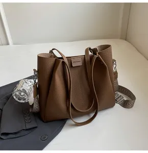 Stylish brown leather bucket bag for women, casual shoulder handbag with wide adjustable strap.