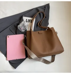 Stylish brown leather bucket bag for women with wide strap and trendy minimalist design.