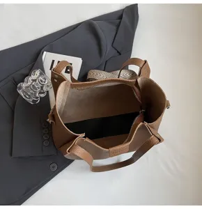 Detailed view of brown leather bucket bag highlighting spacious interior, texture, and woven strap.
