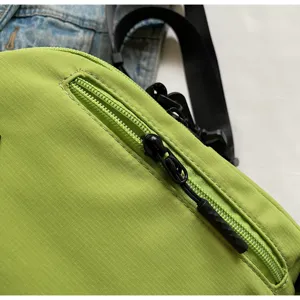 Detailed view of the bright green nylon crossbody bag zipper and high quality fabric.