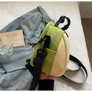 Detailed view of stylish contrast color crossbody bag with black strap and unique knot handle.