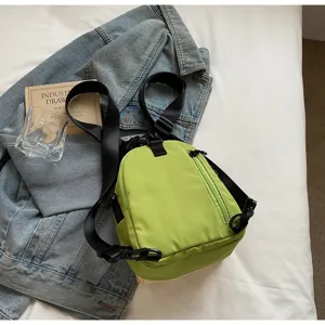 Detail shot of the green shell crossbody bag displayed on a denim jacket lifestyle scene.