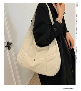 Closeup of a minimalist beige quilted shoulder bag, casual everyday tote design with soft fabric.