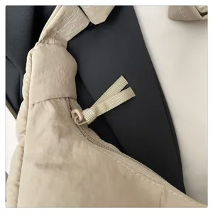 Detailed close-up of a beige nylon crossbody shoulder bag zipper and fabric texture.
