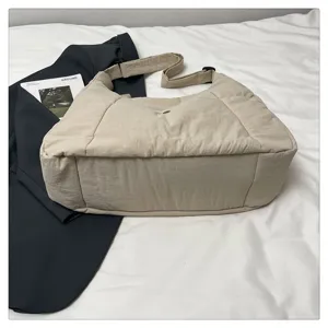 Detailed shot of the lightweight beige quilted shoulder bag featuring adjustable strap and snap.