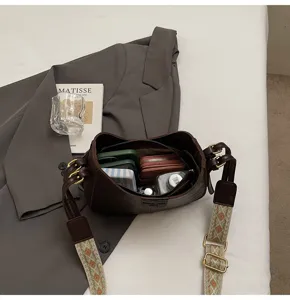 Detail view of a stylish dark brown leather shoulder bag with a patterned wide strap and capacity.